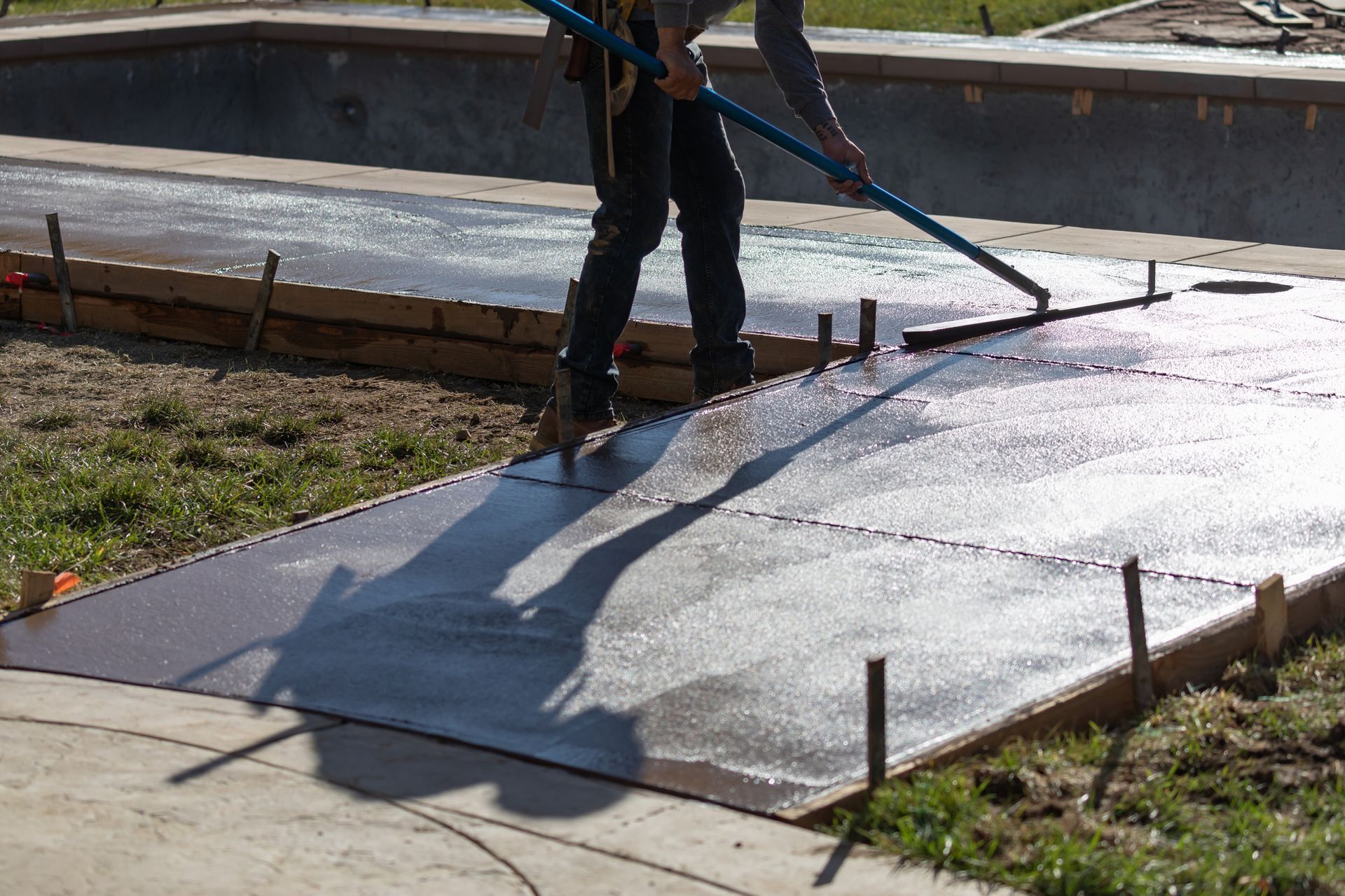 local concrete contractor using a manual concrete floor scraper to create a smooth finish